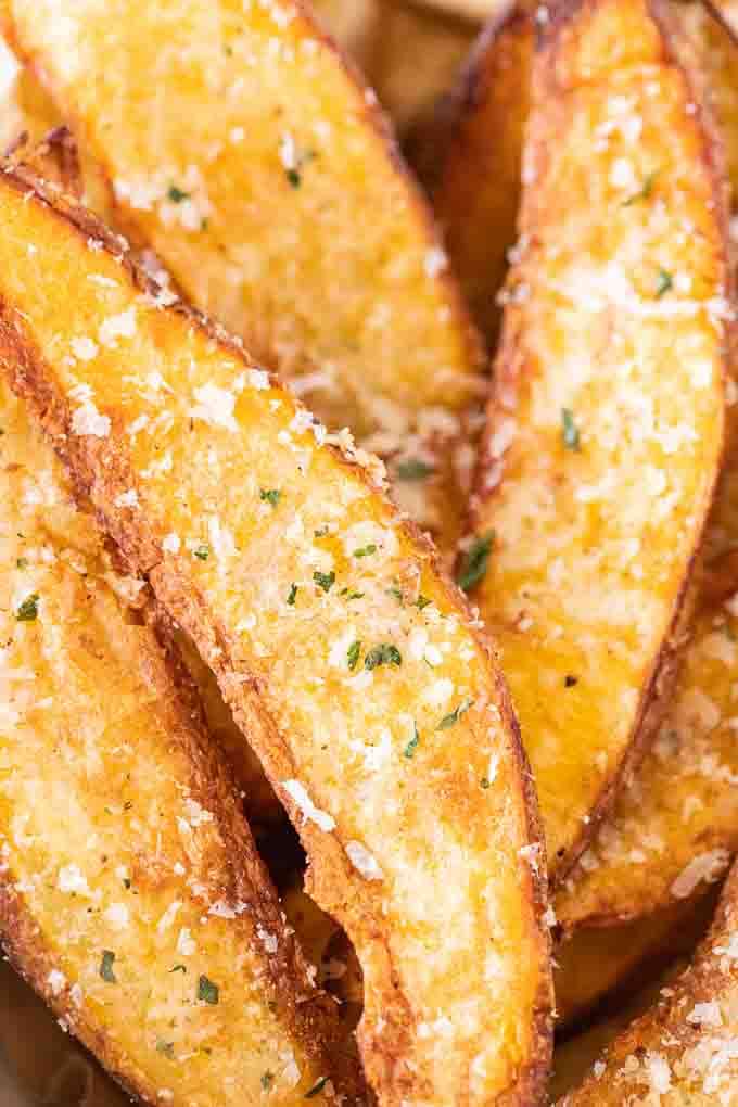 Gros plan sur des quartiers de pommes de terre à la friteuse à air, garnis de Parmigiano