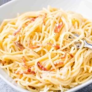 Spaghetti Carbonara sur une assiette blanche avec une fourchette.
