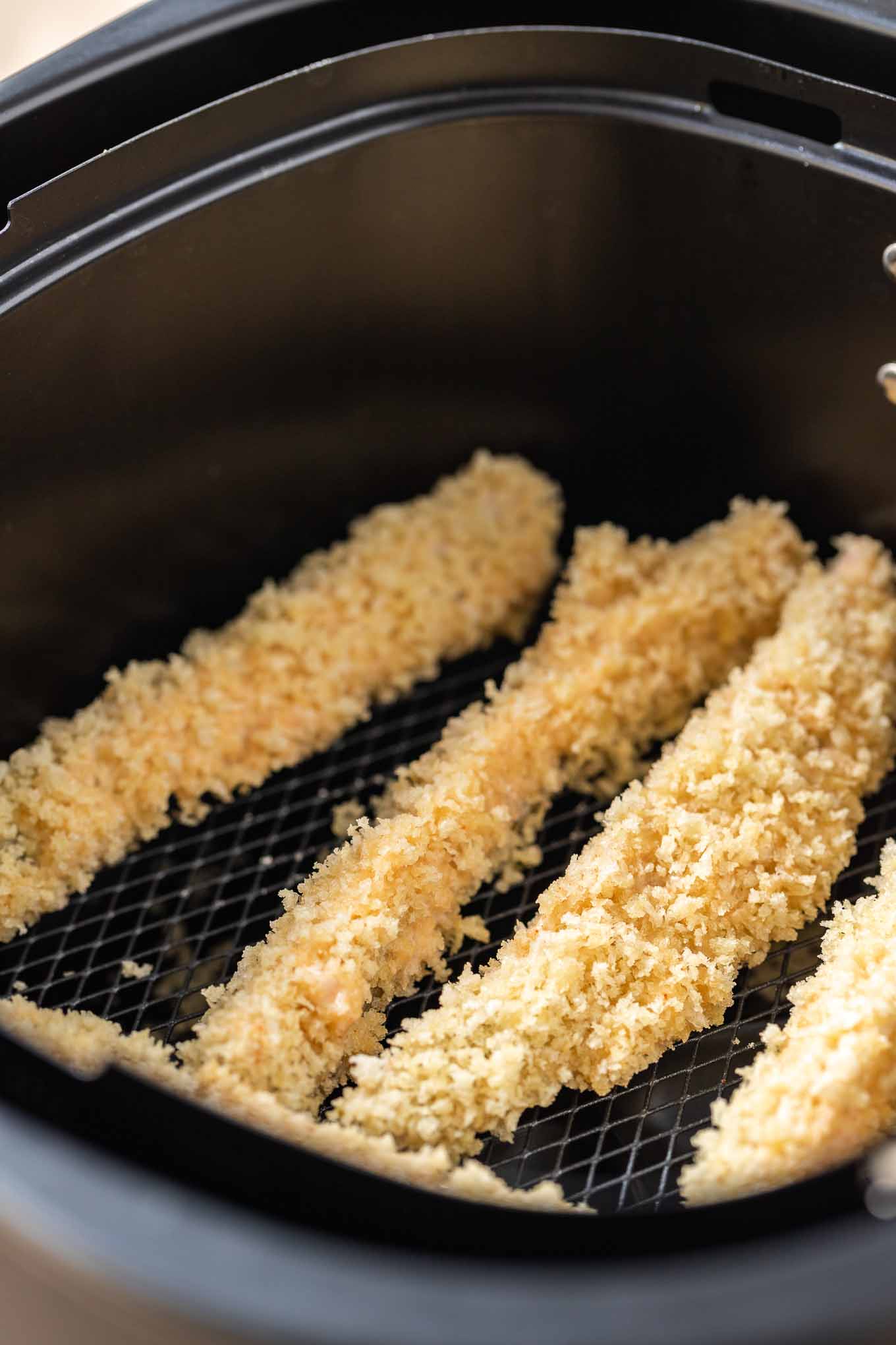 Les cornichons à la friteuse à air sont super croustillants et constituent un excellent en-cas pour le jour de match ou une fête ! Les cornichons frits à la friteuse à air sont plus sains car ils sont faits avec beaucoup moins d'huile et ont une couche de chapelure panko qui les rend encore meilleurs que l'original frit. #RecettesFriteuseÀAir #CornichonsFrits Des quartiers de cornichons panés dans un panier de friteuse à air.