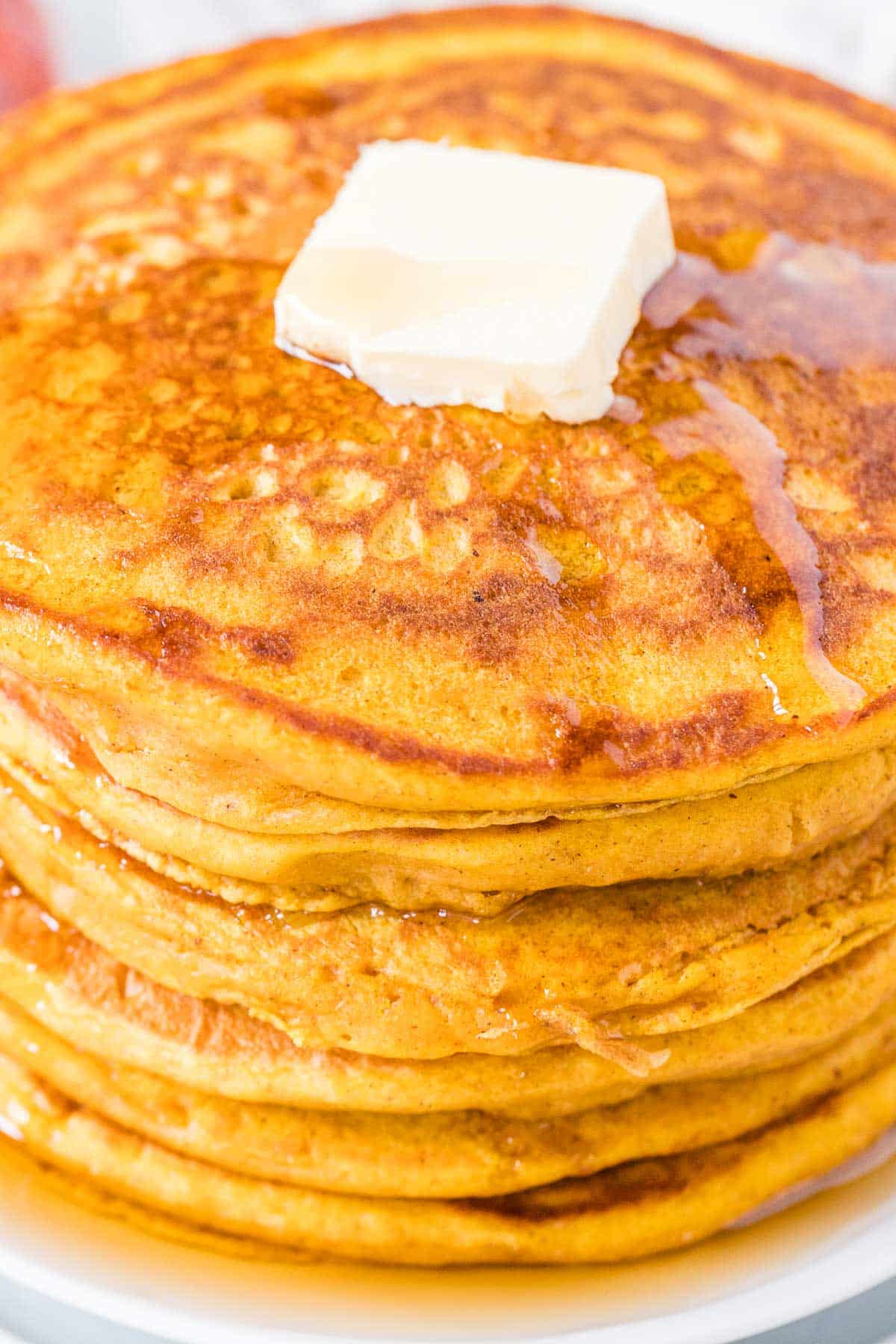 Gros plan sur des crêpes à la citrouille empilées dans une assiette.