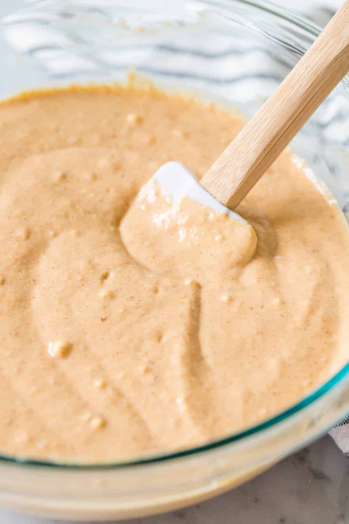 Bol en verre avec la pâte à crêpes à la citrouille avec une spatule.