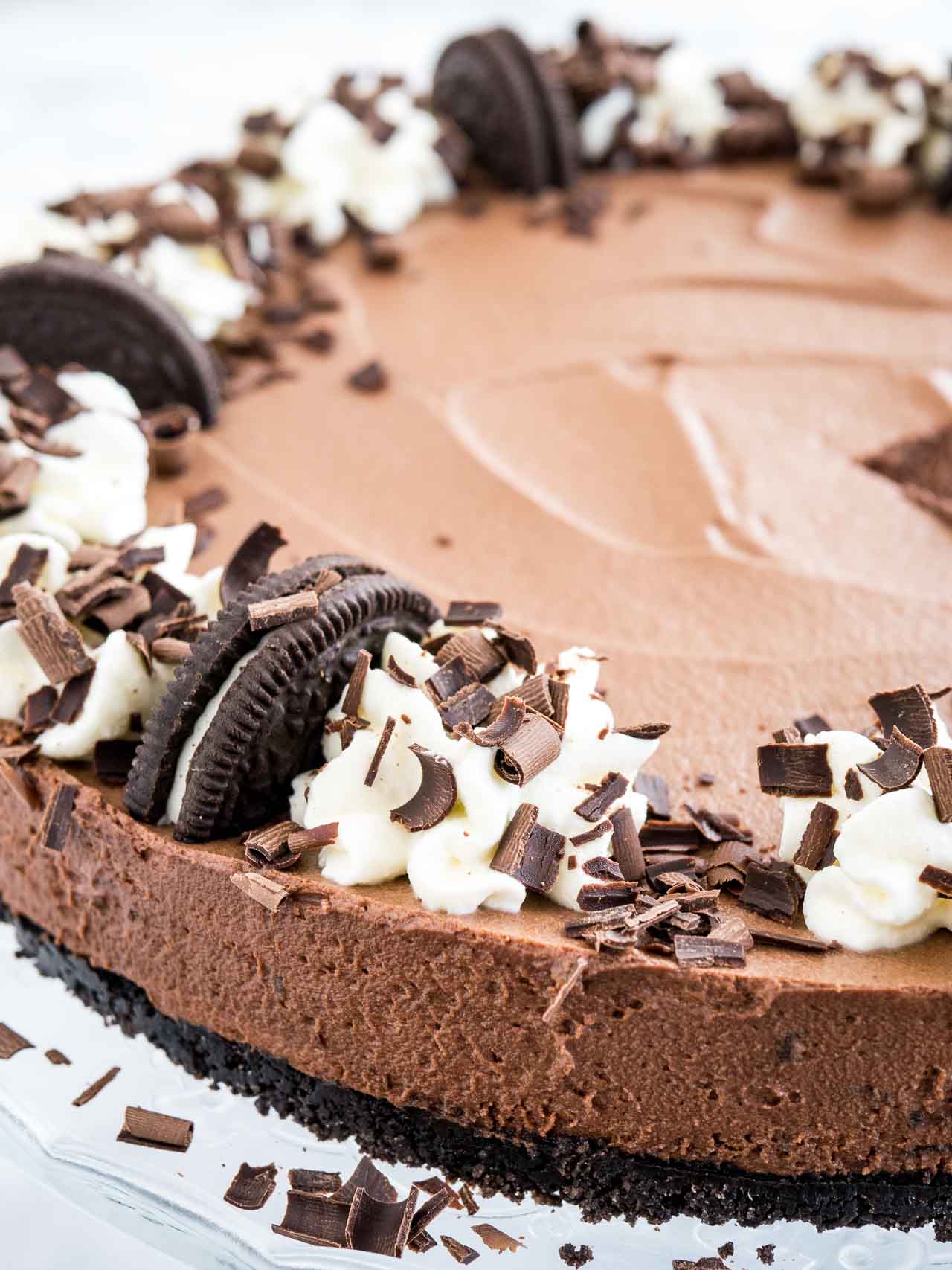 Ce gâteau au chocolat mousse est le rêve de tout amateur de chocolat et peut être préparé à l'avance ! Une croûte en Oreo remplie d'une mousse au chocolat décadente surmontée de plus d'Oreos, de crème fouettée faite maison et de copeaux de chocolat. Ce dessert sans cuisson est parfait pour des occasions spéciales mais si facile à préparer à partir de zéro ! #dessertsanscuisson #gâteauauchocolatmousse #mousseauchocolat #chocolat #recettes #desserts #gâteau Gros plan de gâteau au chocolat mousse avec croûte Oreo, garni de moitiés de biscuits Oreo, crème fouettée et copeaux de chocolat.