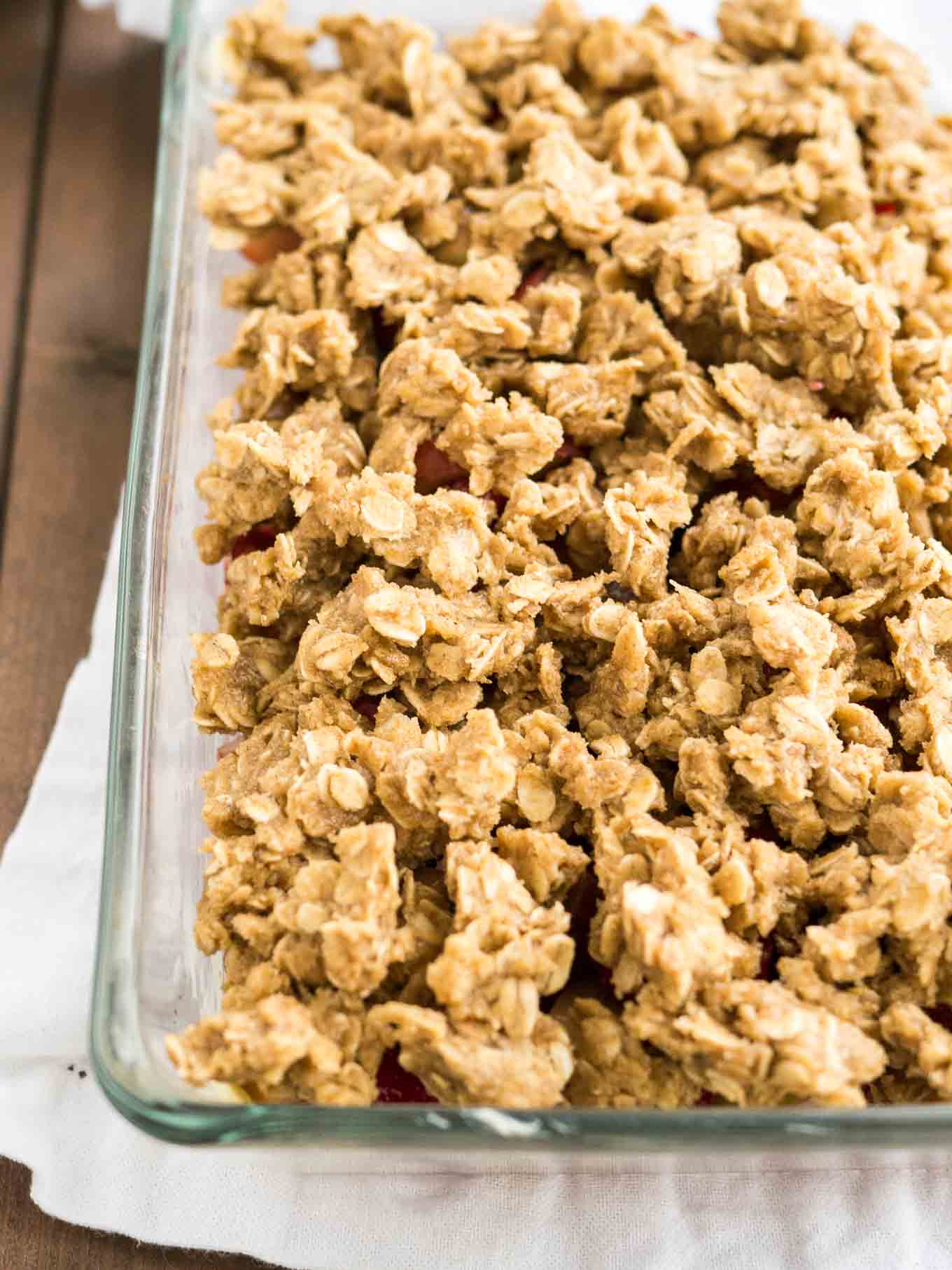 Garniture de crumble aux flocons d'avoine pour le crumble de rhubarbe dans un plat en verre sur une table en bois.