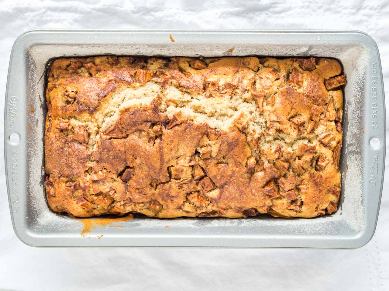 Un moule à pain fariné avec du pain aux pommes et à la cannelle cuit.
