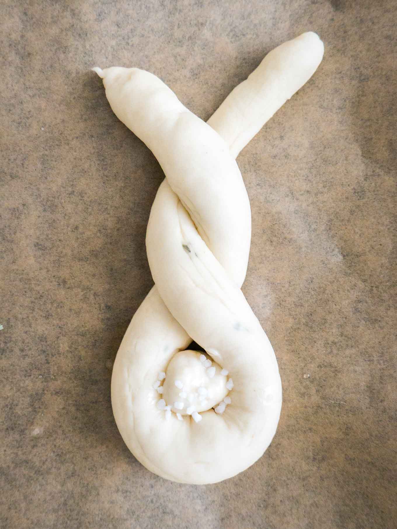 Pâte façonnée en forme de lapin, avec une queue en pâte sur du papier brun.
