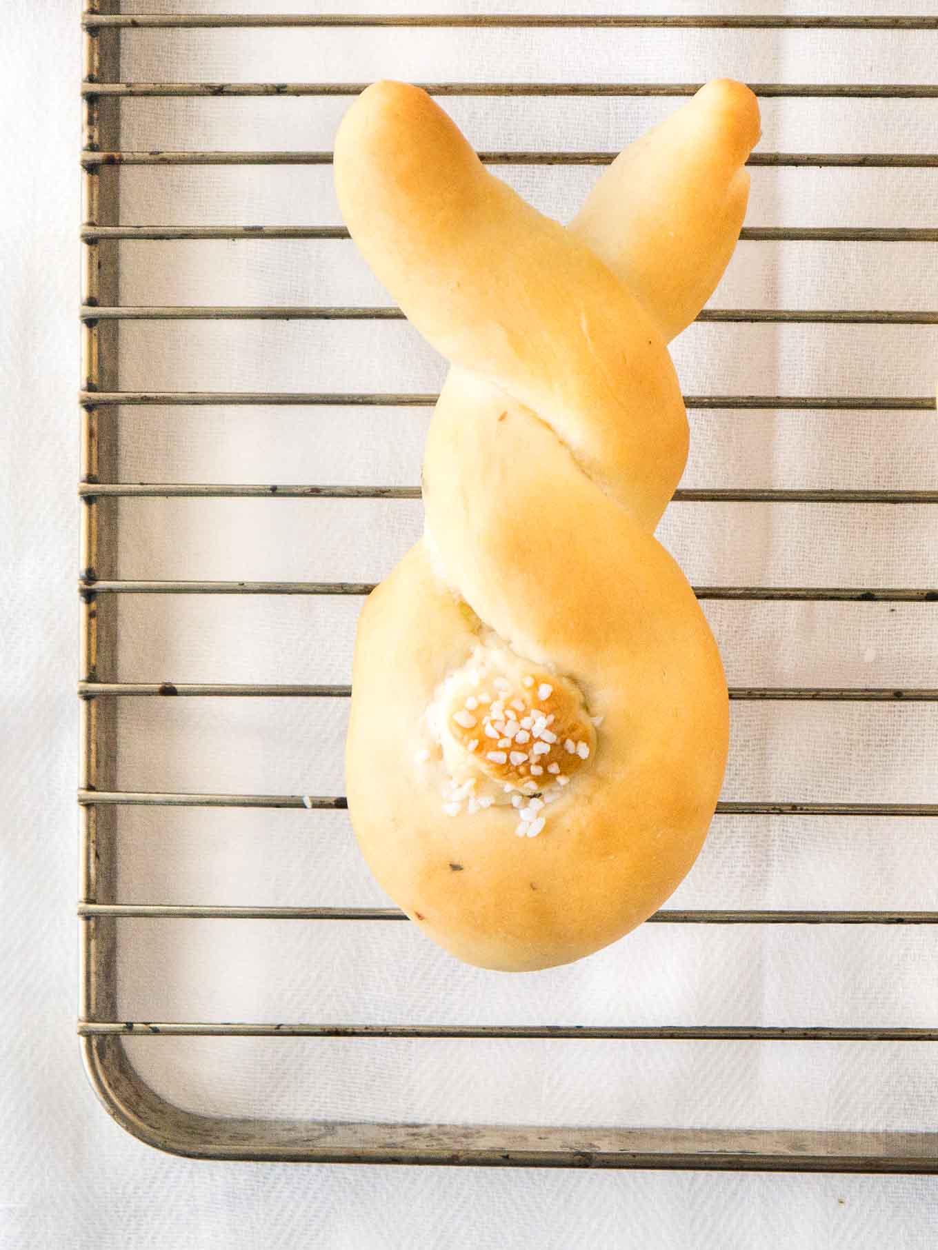 Pain en forme de lapin, avec une queue en pâte sur une grille en acier inoxydable.