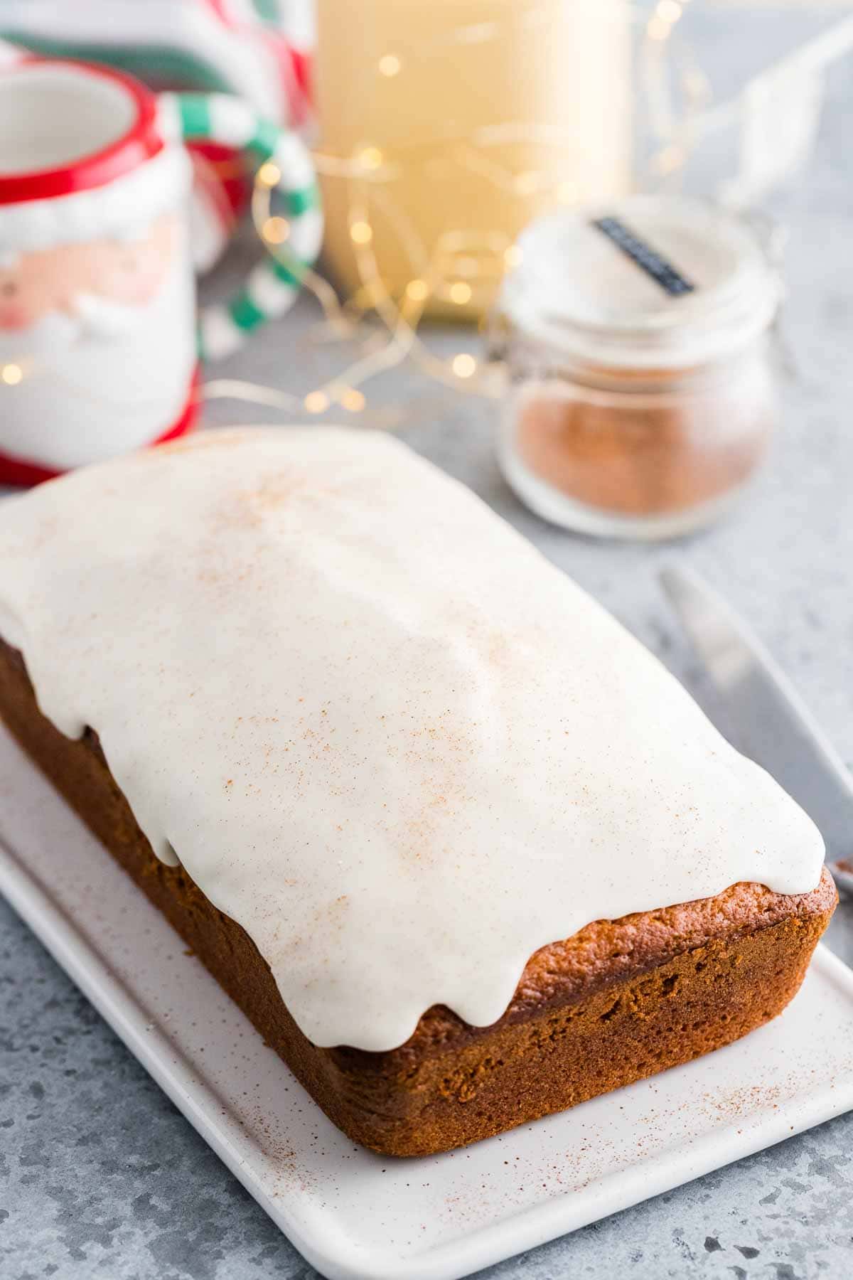 Une vue latérale d'un pain rapide à l'œuf de Noël avec un glaçage blanc et de la noix de muscade sur le dessus.