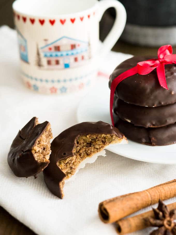 Une pile de Lebkuchen sur une assiette blanche, attachée par un ruban rouge. À côté, une tasse de café et un Lebkuchen cassé en deux.