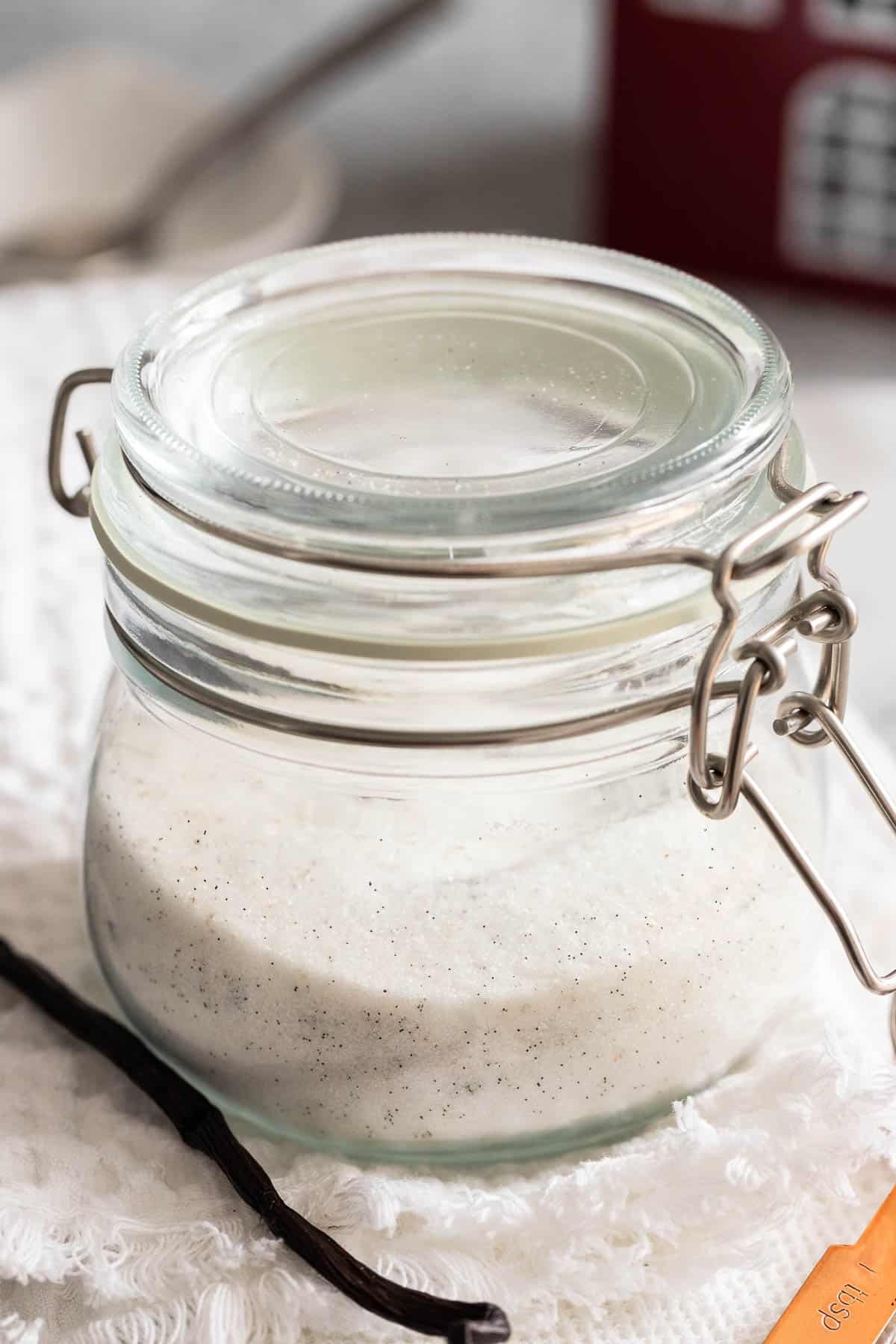 Un pot fermé rempli de sucre et de gousses de vanille.