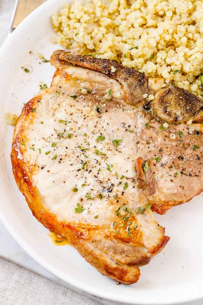 Gros plan de côtelettes de porc à la friteuse à air avec quinoa dans une assiette.