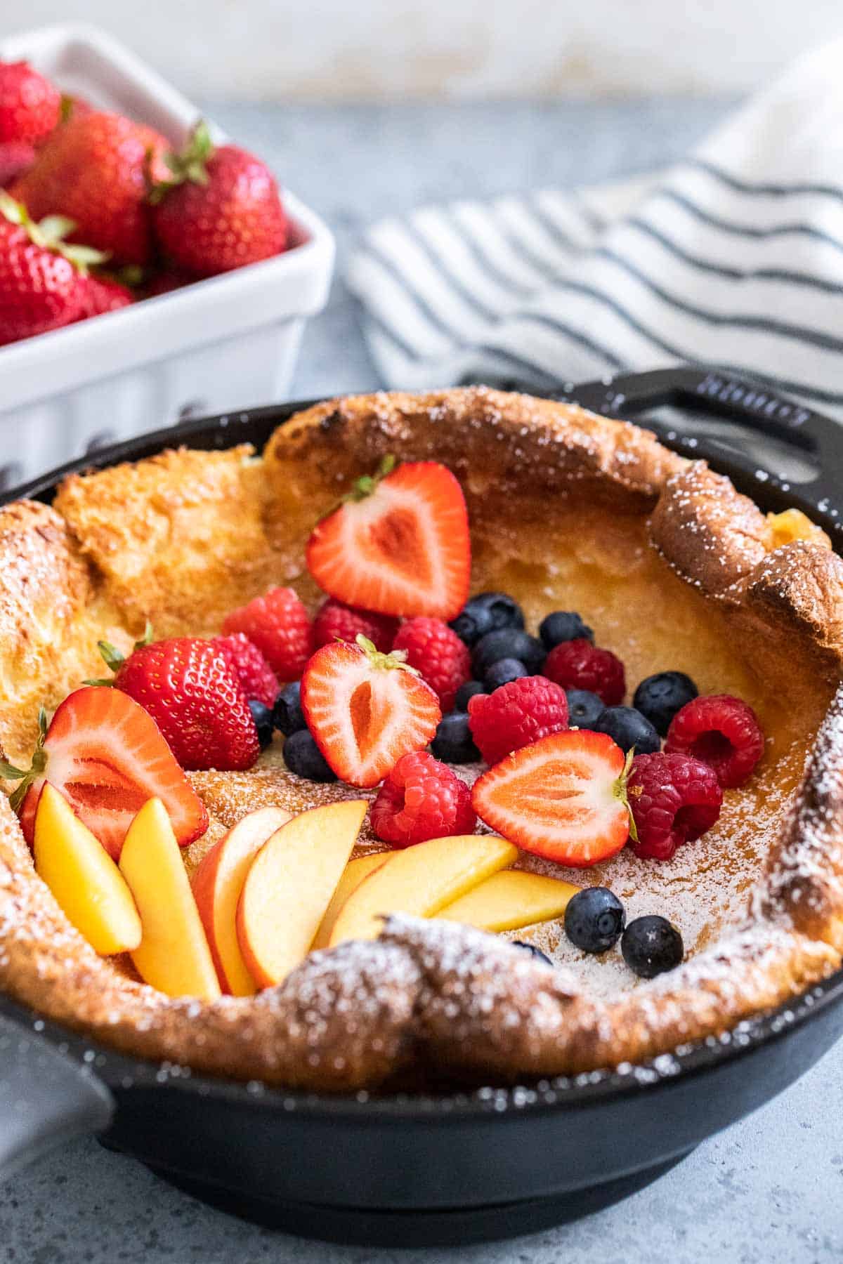 Un pancake néerlandais dans une poêle en fonte garni de fruits.