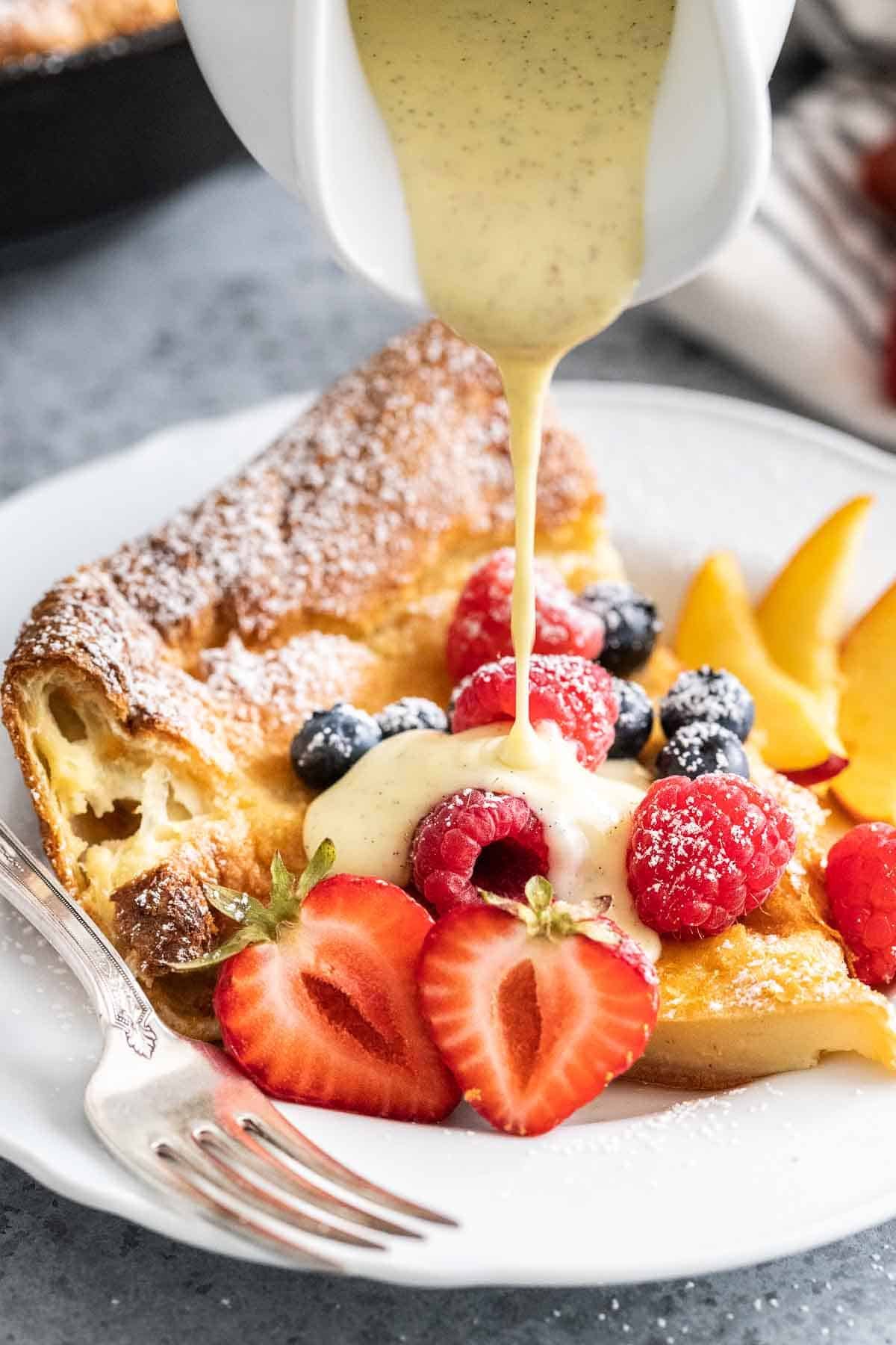 De la sauce à la vanille versée sur une part de pancake néerlandais.