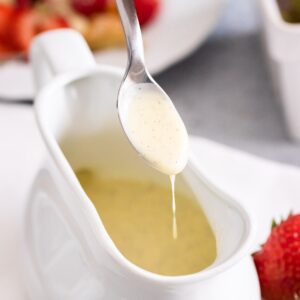 De la sauce vanille qui goutte d'une cuillère dans un bol.