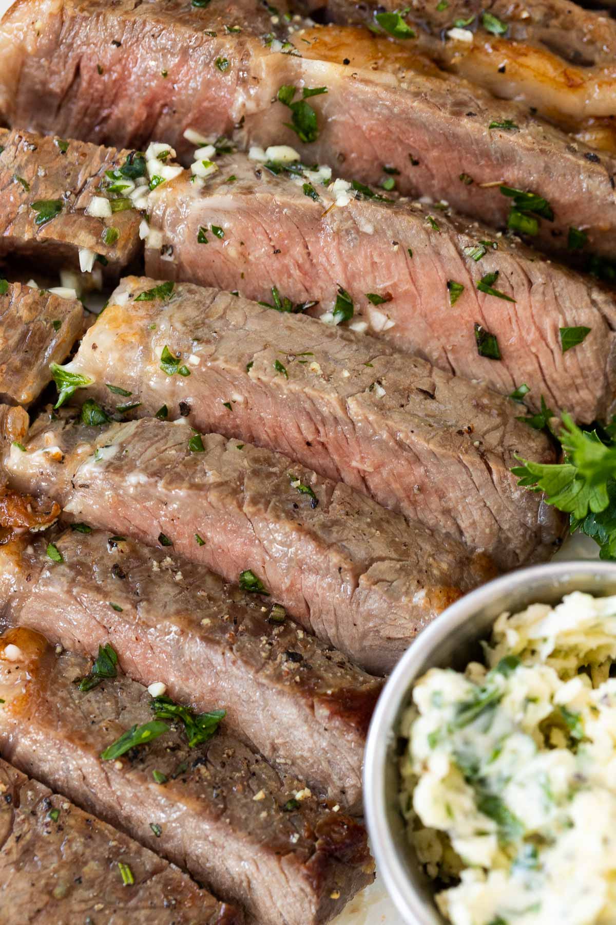 Un steak découpé à point à côté d'un petit bol de beurre à l'ail.