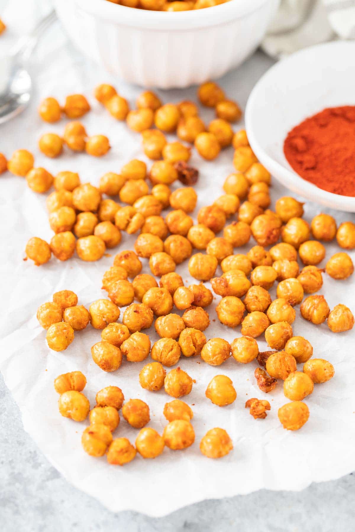 Pois chiches croustillants sur du papier sulfurisé à côté d'un bol de paprika
