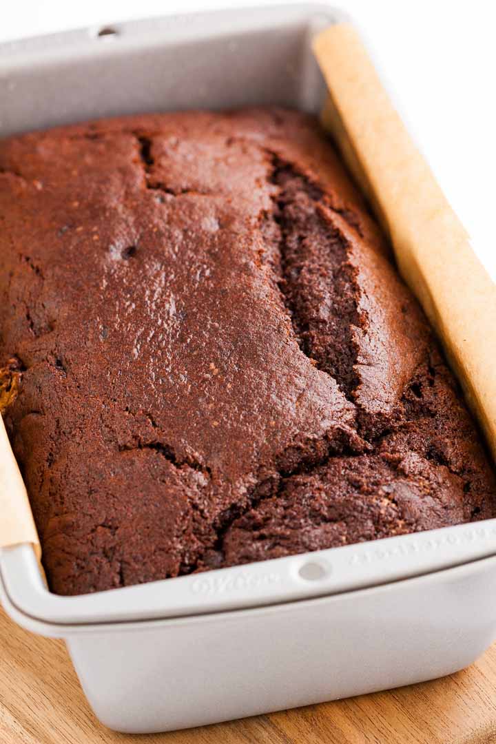 Un moule à pain, tapissé de papier sulfurisé, contenant un pain à la banane et au chocolat.