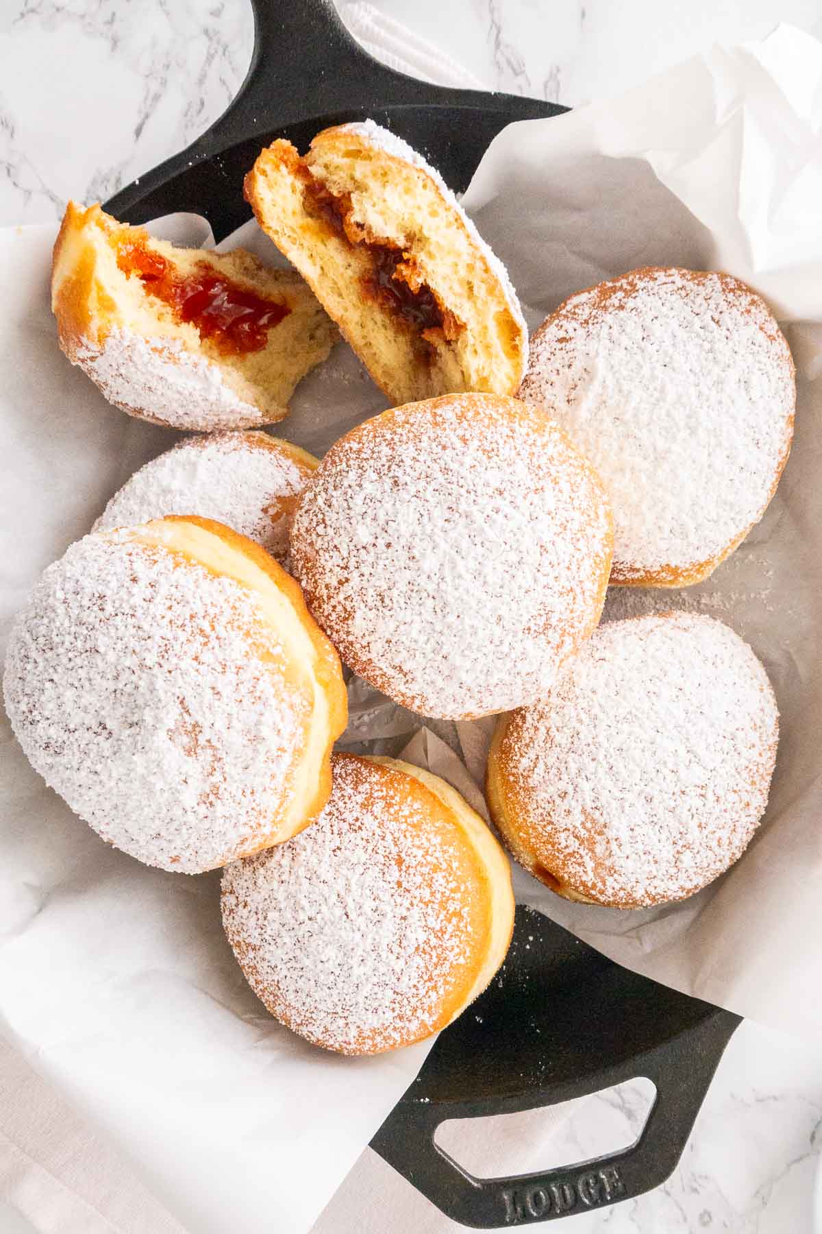 Beaucoup de beignets allemands dans une poêle recouverte de papier sulfurisé.