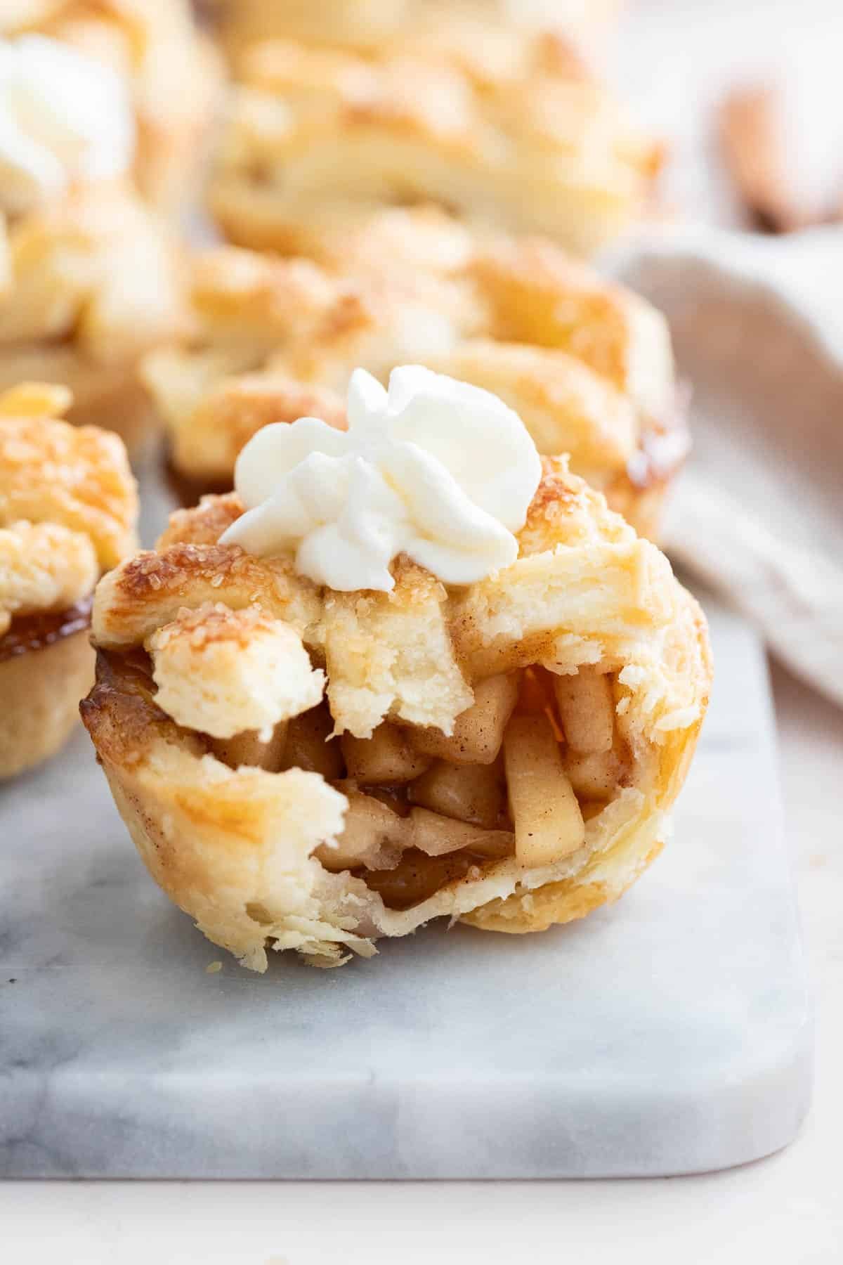 Une mini tarte aux pommes avec une bouchée prise dans un plateau en marbre.