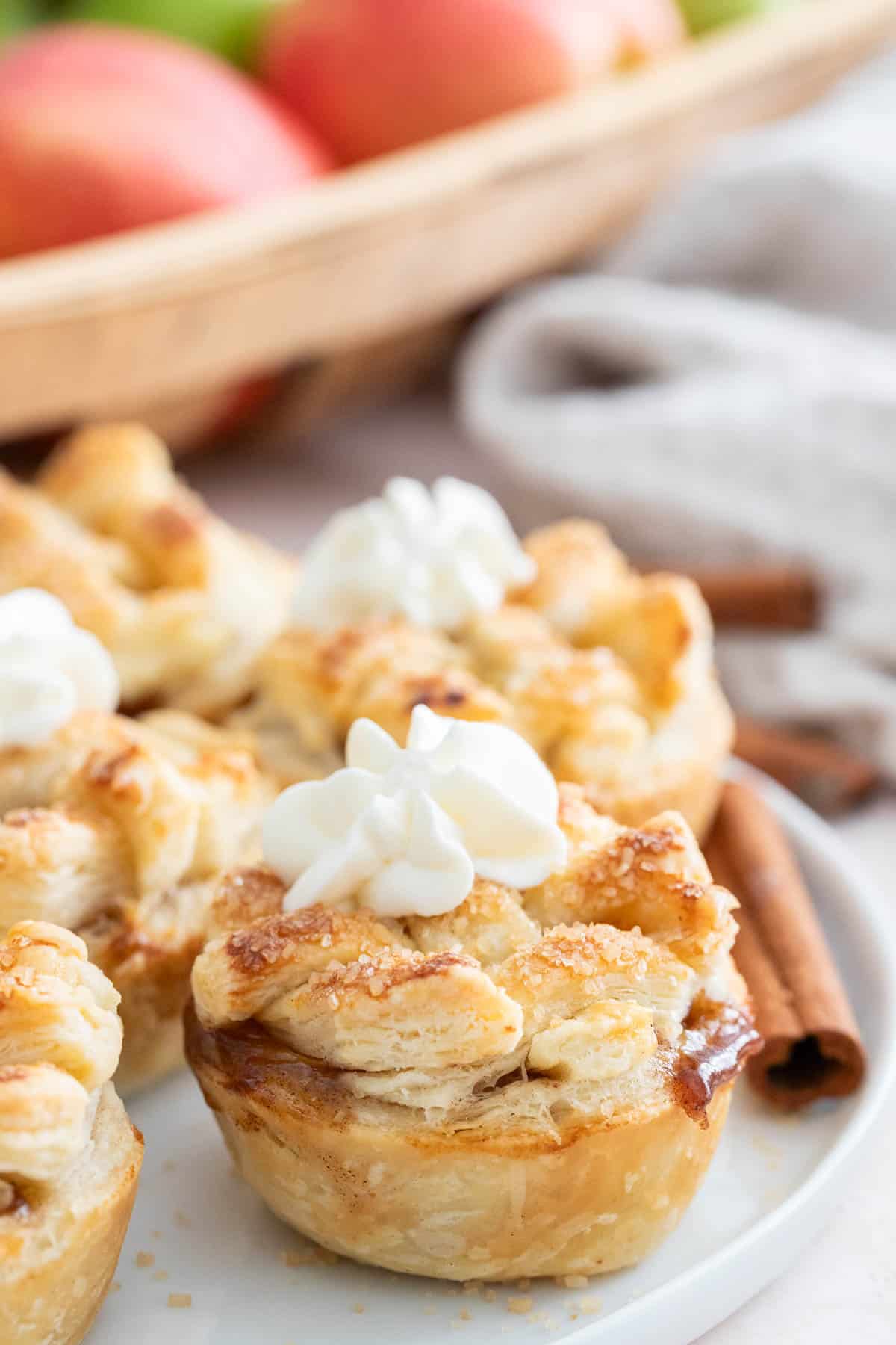 Une assiette blanche remplie de mini tartes, décorées avec de la crème fouettée.