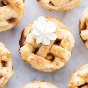 Mini tartes aux pommes décorées avec de la crème fouettée.
