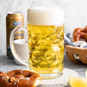 Une chope de bière à côté d'un bretzel et d'une tranche de citron.