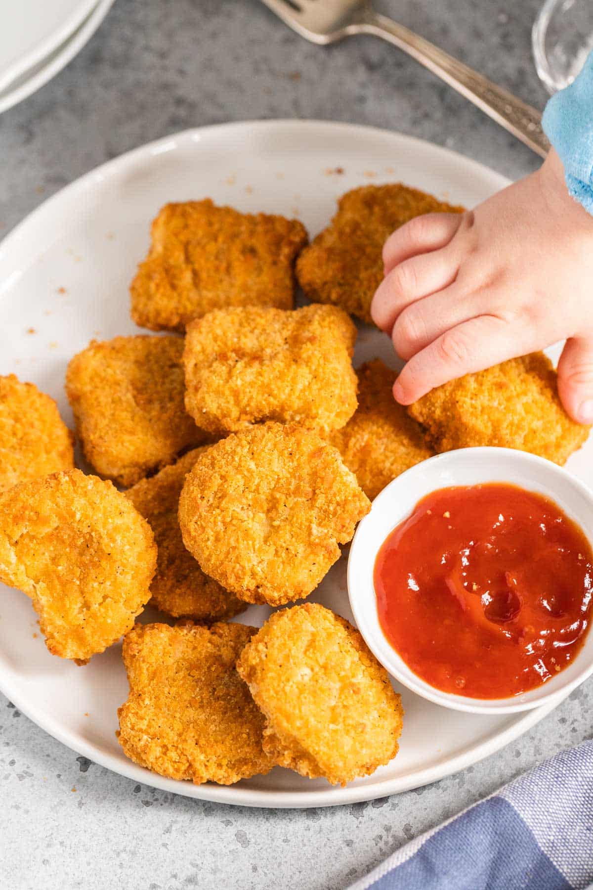 Une main d'enfant prenant un nugget de poulet.