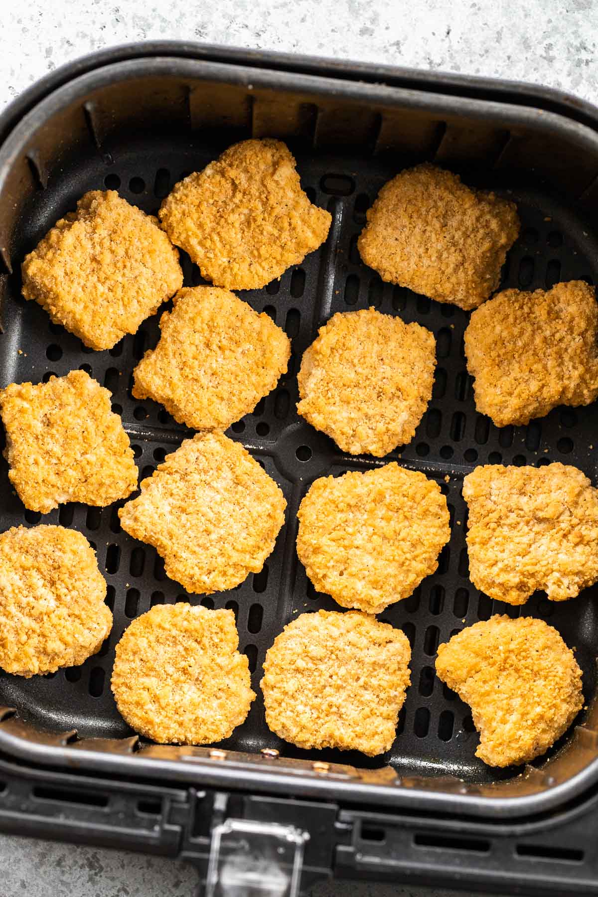 Nuggets de poulet congelés dans un panier de friteuse à air.