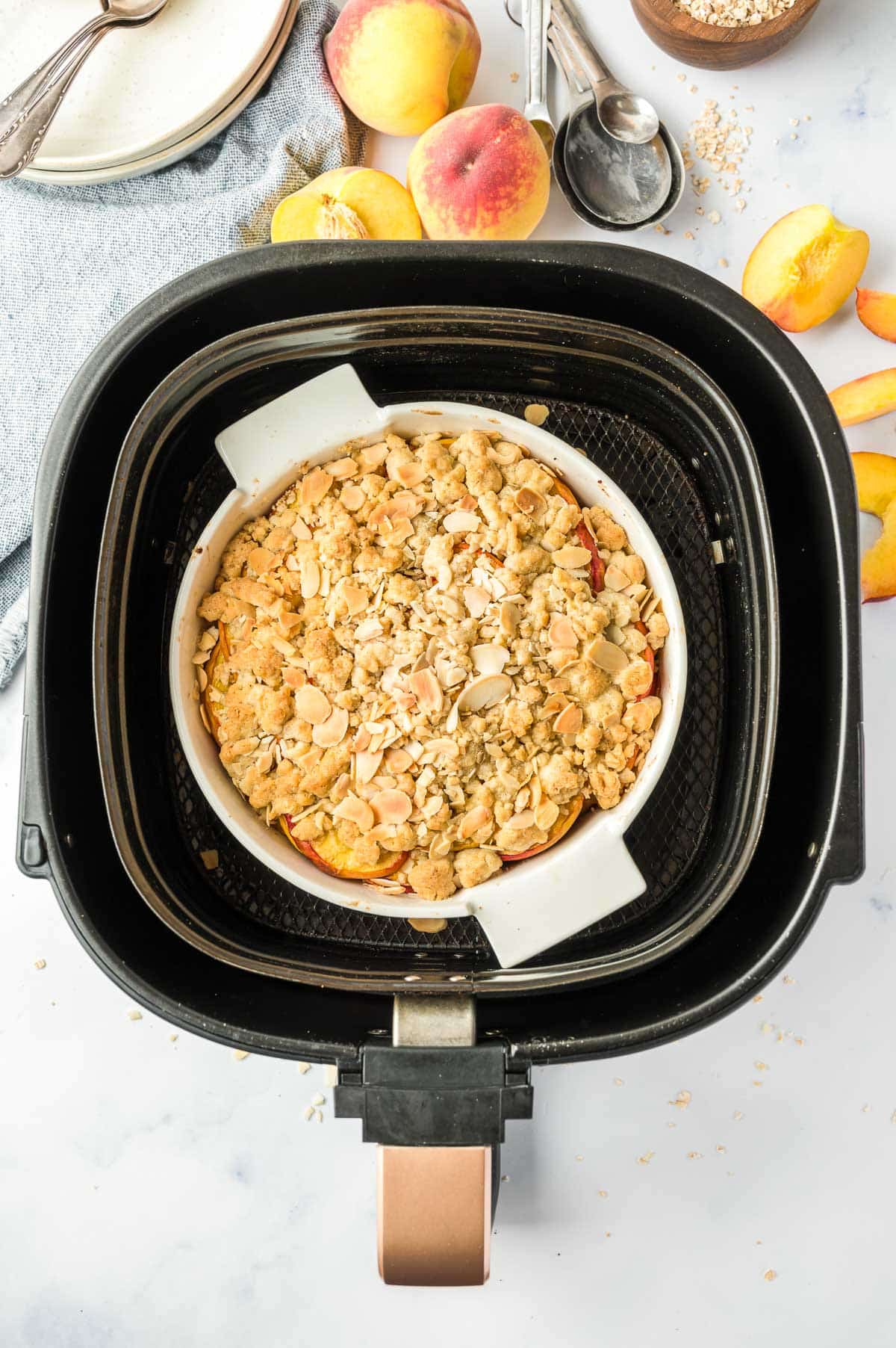 Un crumble de pêche cuit dans un plat de cuisson dans un panier d'air fryer