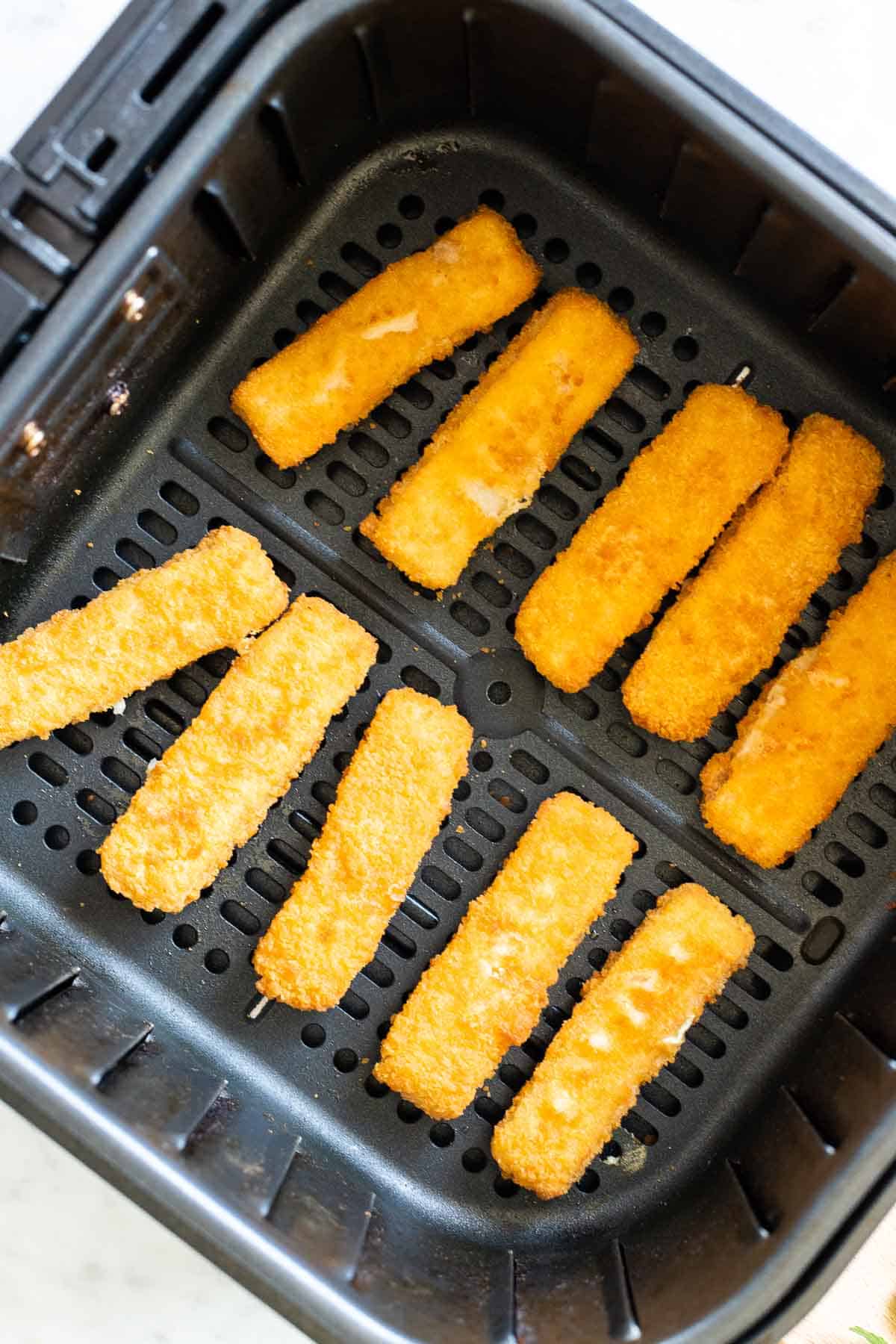 Bâtonnets de poisson cuits dans un panier de friteuse à air.