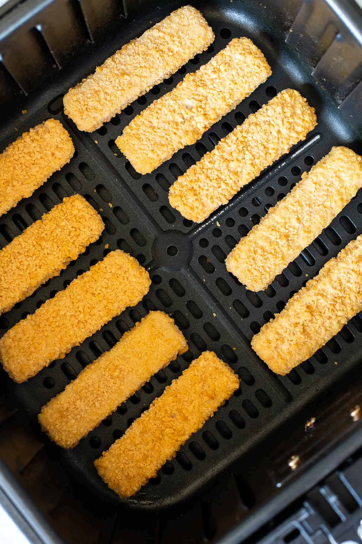 Bâtonnets de poisson surgelés dans un panier de friteuse à air.