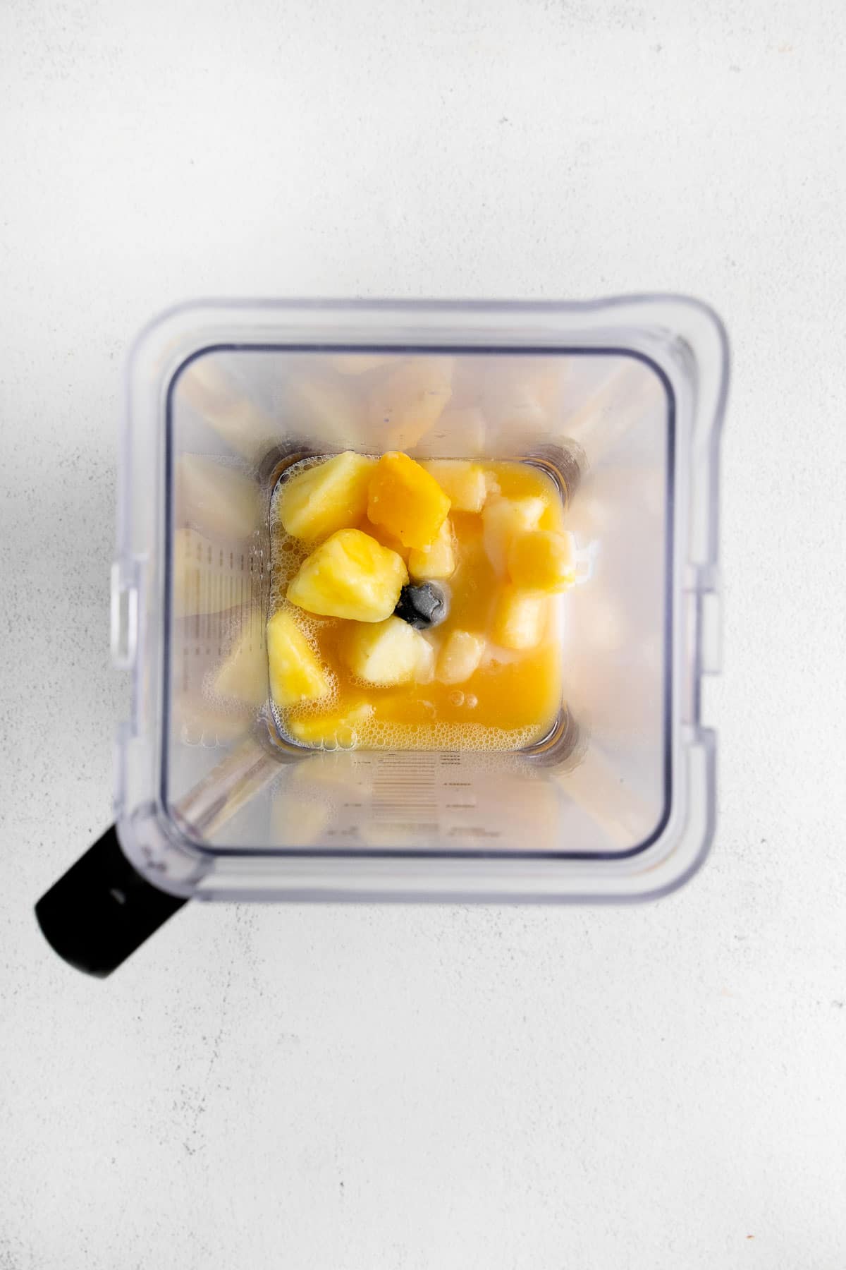 Ananas congelé, jus d'ananas et crème de noix de coco dans un mixeur.