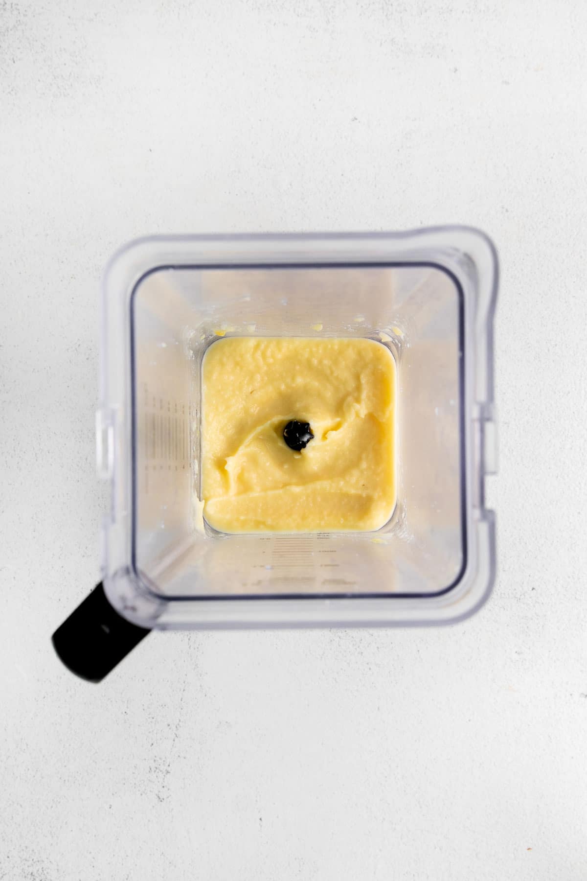 Ingrédients pour une piña colada non alcoolisée mélangés dans un récipient de mixeur.
