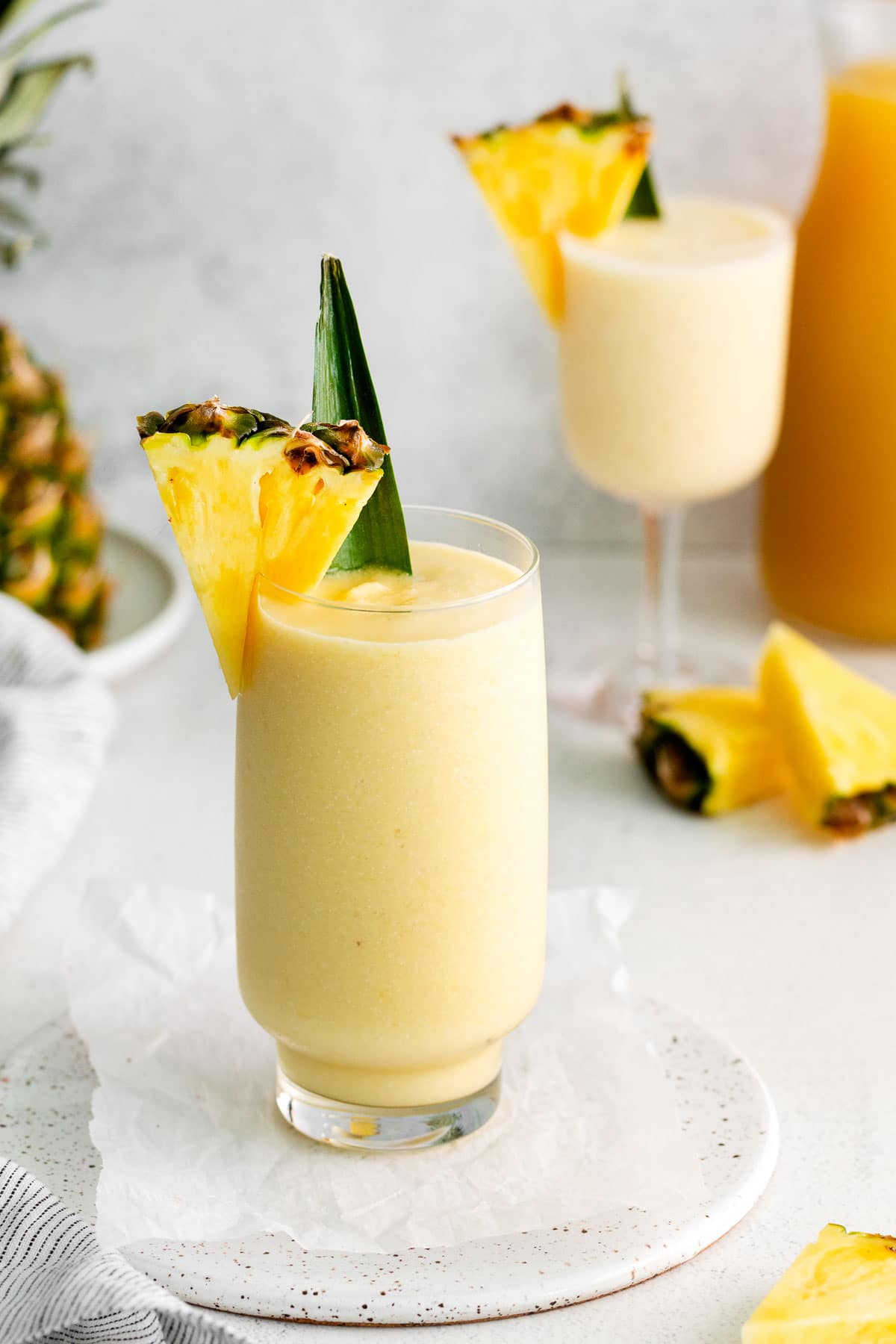 Deux verres remplis d'une boisson jaune pâle à côté d'un ananas.