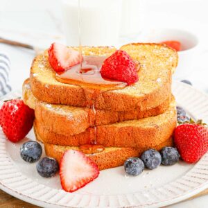 Sirop versé sur du pain perdu garni de fruits.