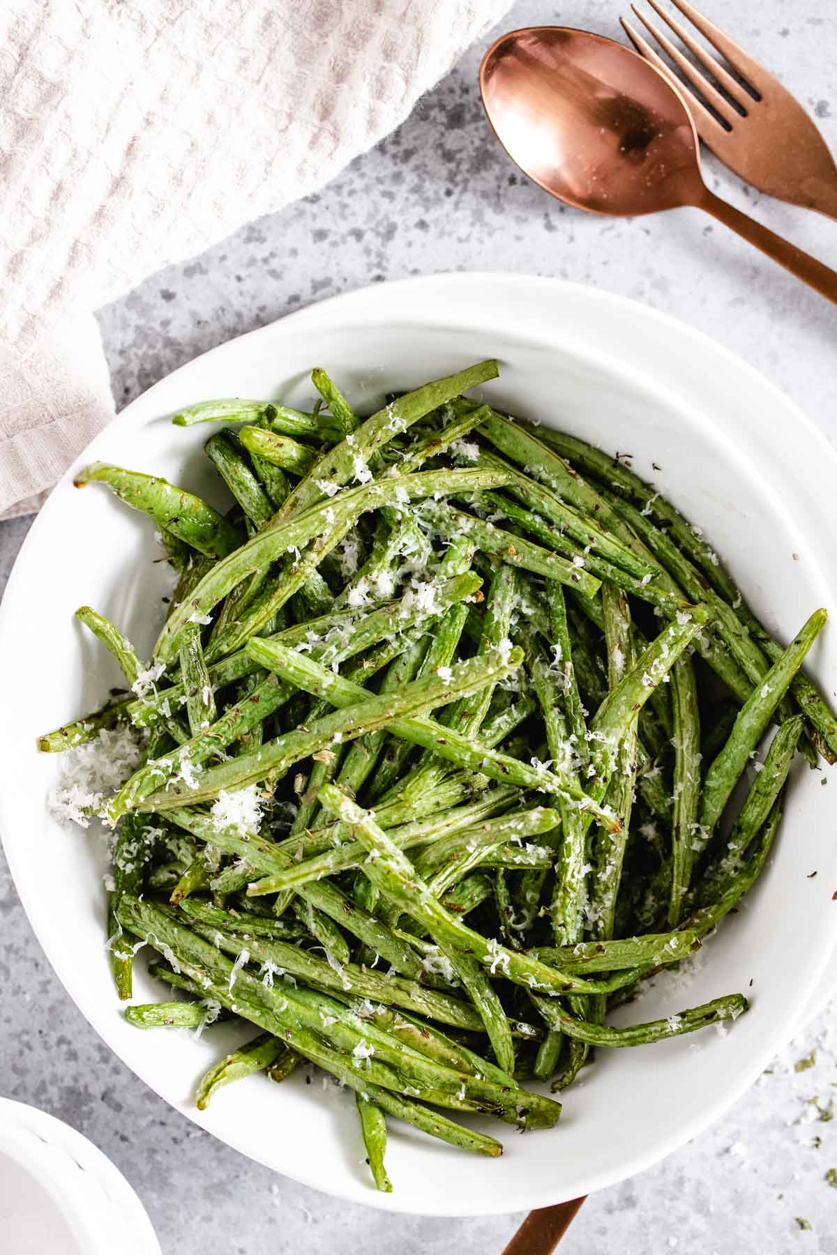vue du dessus d'un bol blanc rempli de haricots verts frits à l'air sur un fond gris