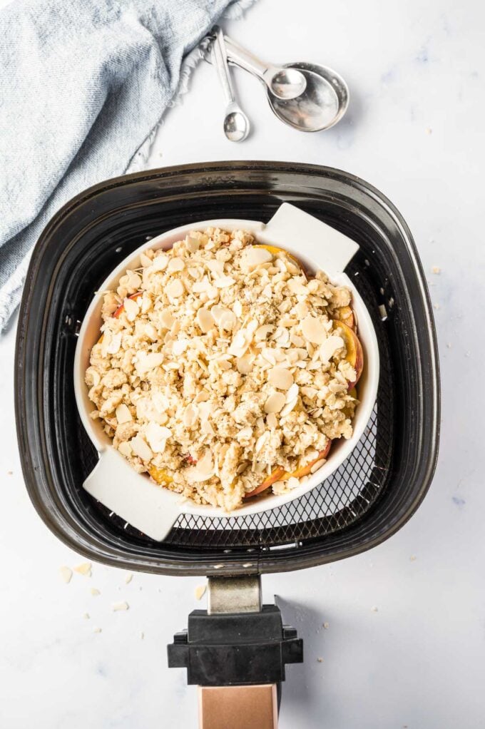 Un croustillant de pêches assemblé dans un plat de cuisson dans un panier de friteuse à air
