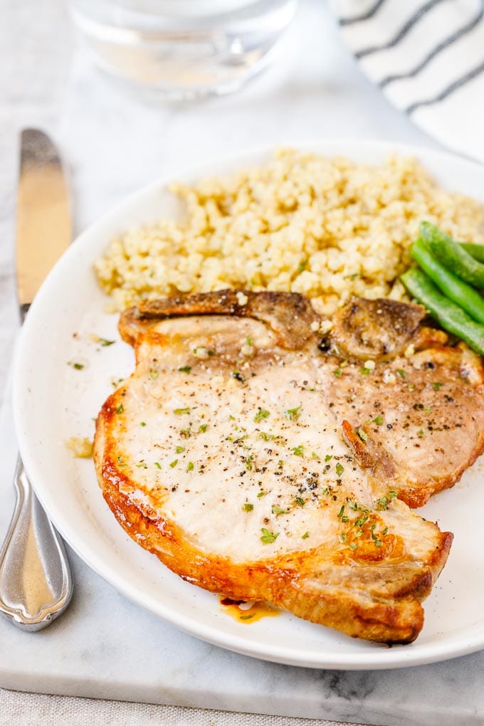 Une assiette avec des côtelettes de porc à la friteuse à air, quinoa et haricots verts.