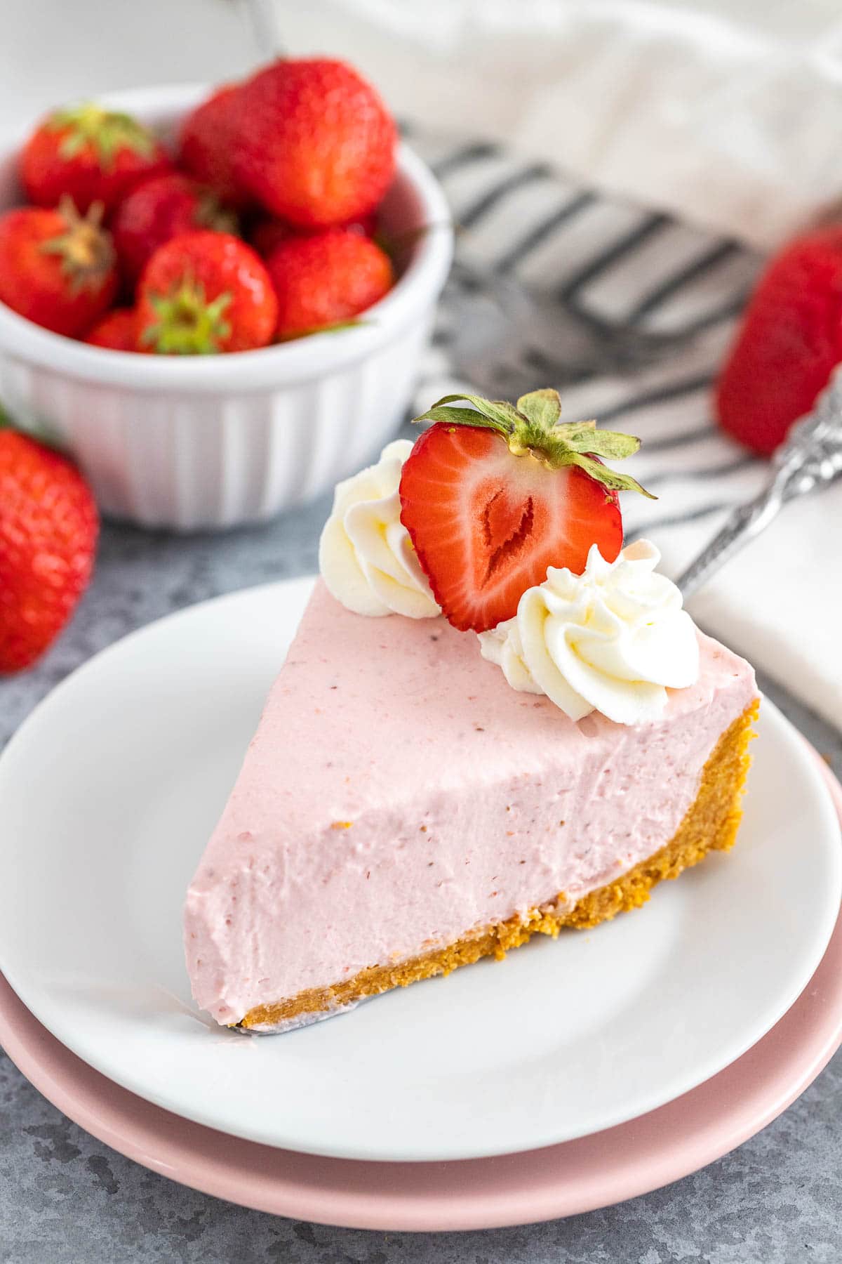 Une part de cheesecake aux fraises sur une assiette blanche.
