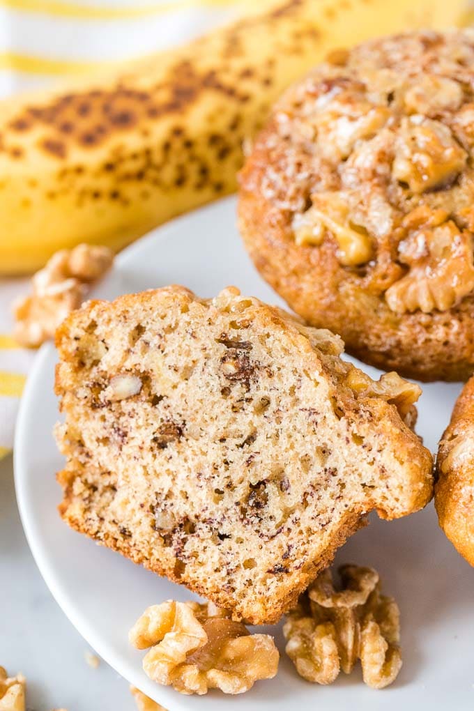 Muffins à la banane et aux noix sur une assiette avec une banane en arrière-plan.
