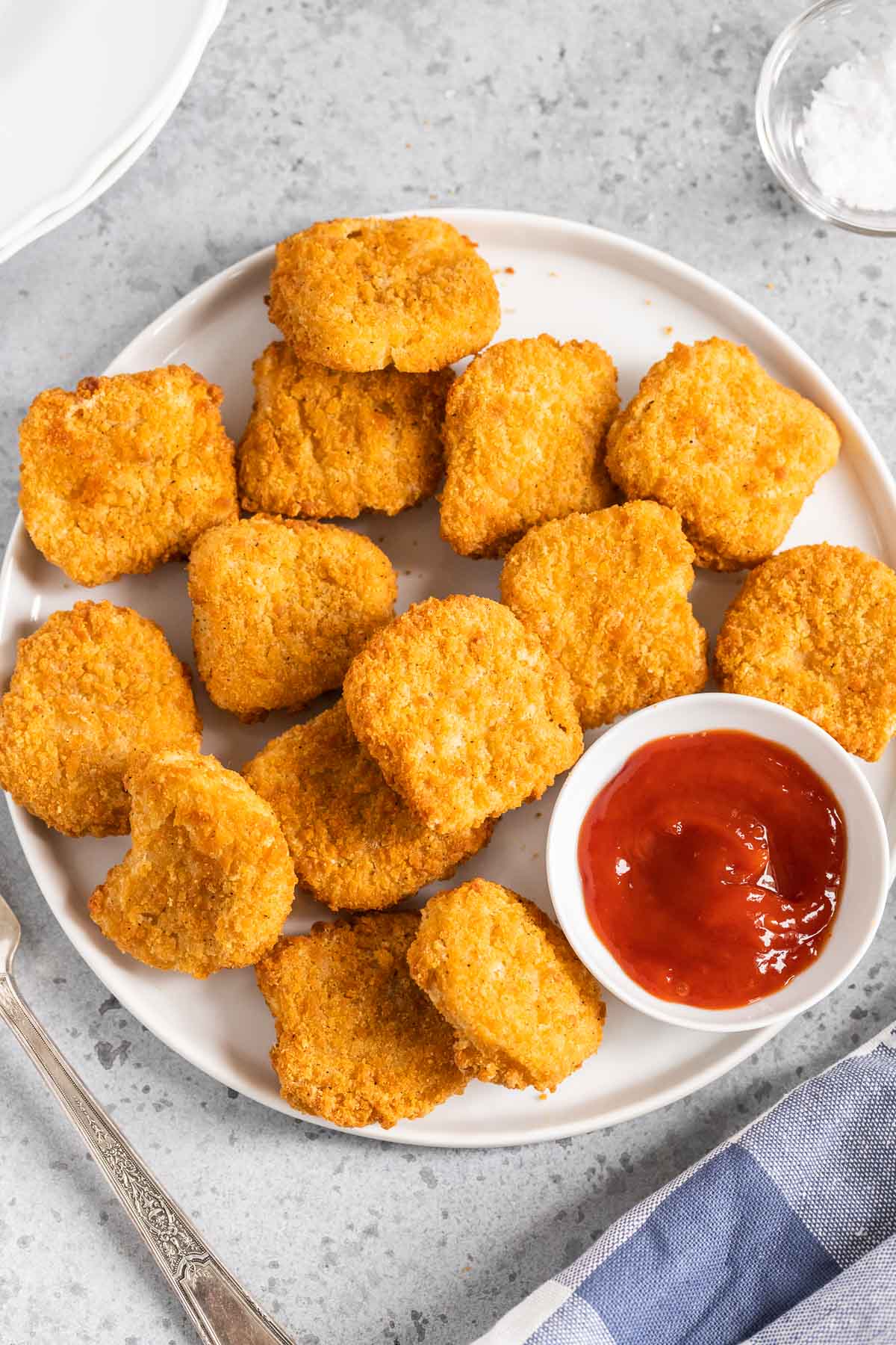 Nuggets de poulet sur une assiette blanche avec un petit bol de ketchup.