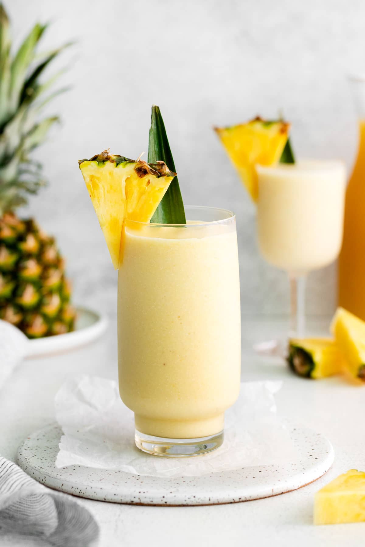 Un grand verre rempli de piña colada vierge, garni d'un morceau d'ananas et d'une feuille.