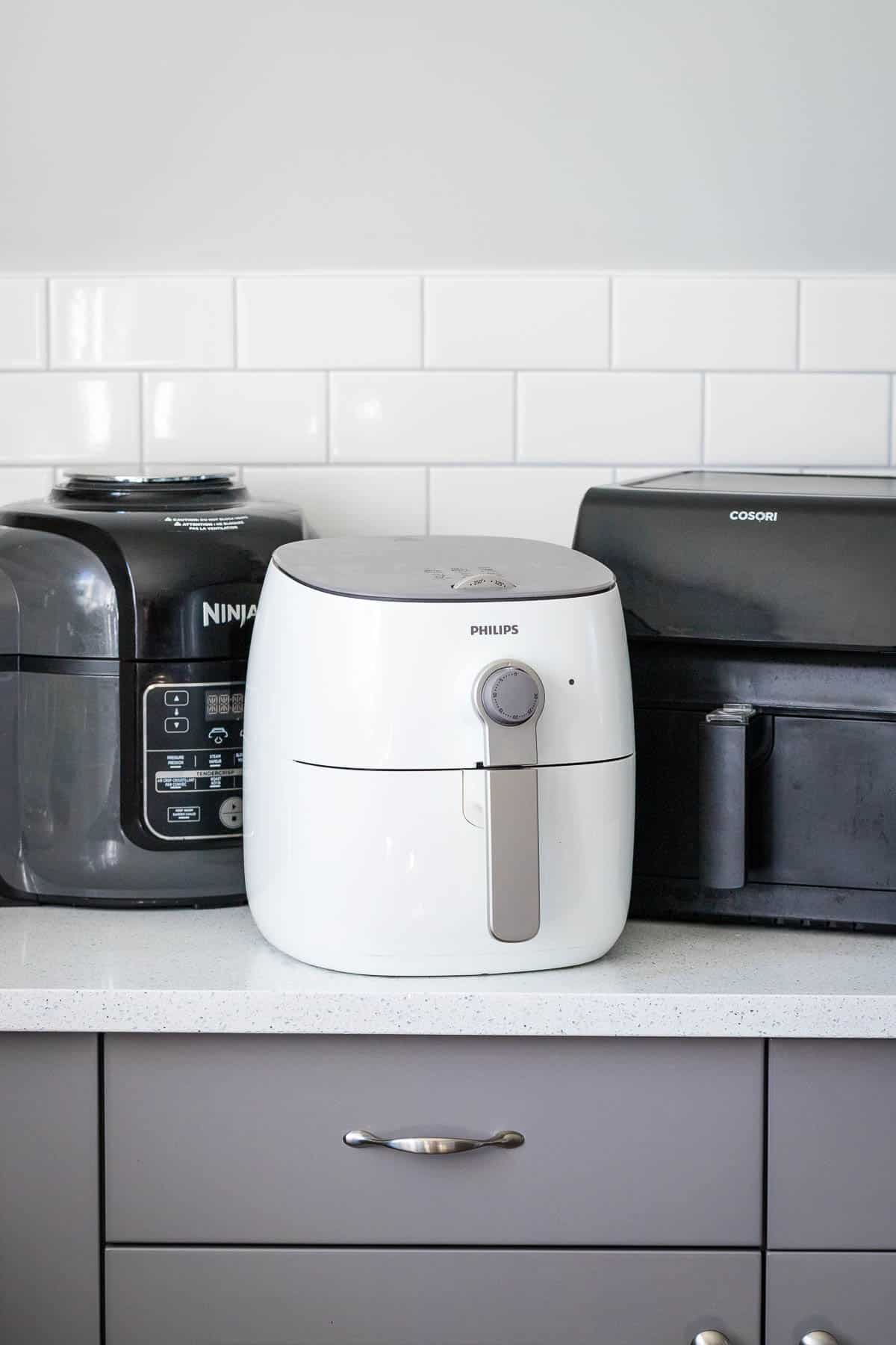 Trois air fryers sur un plan de travail de cuisine