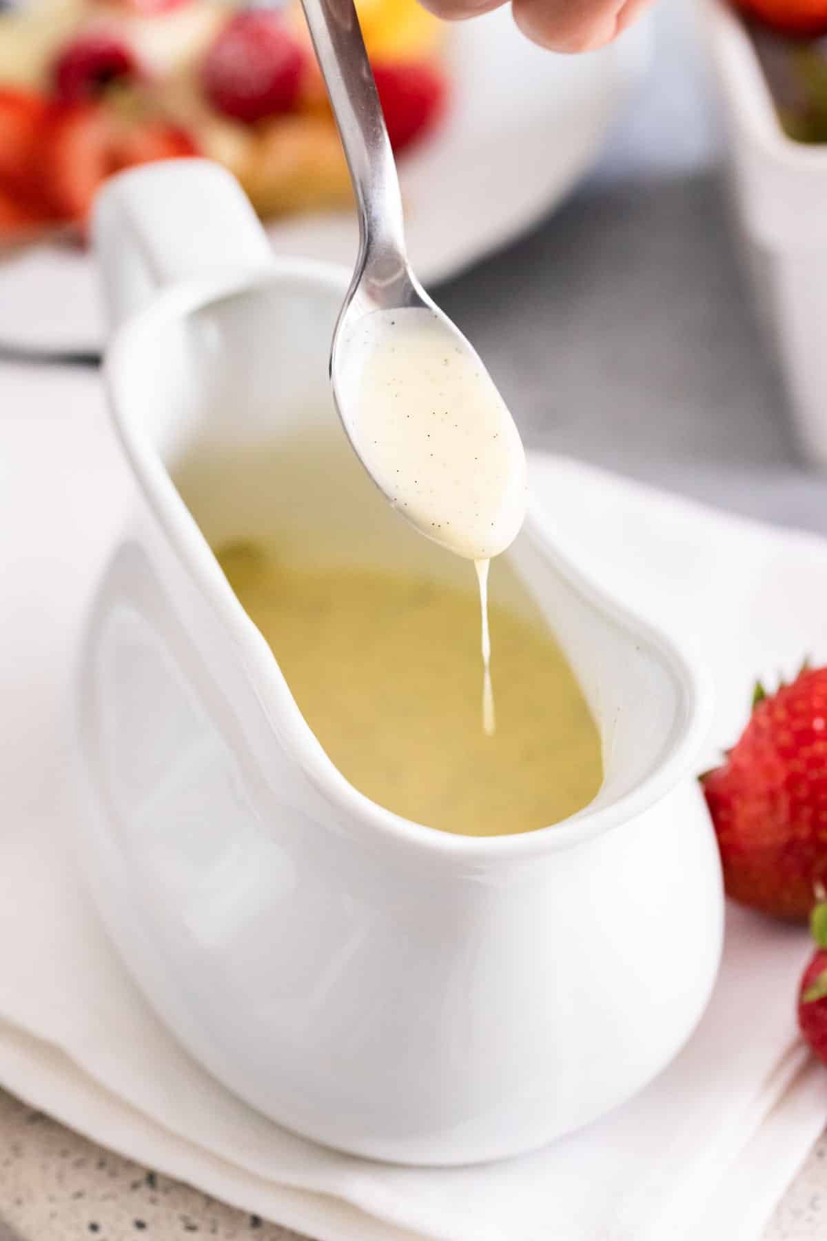 De la sauce vanille qui goutte d'une cuillère dans un bol.