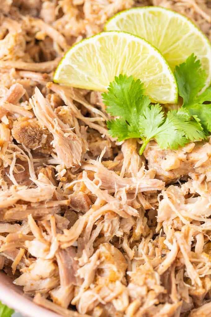 Gros plan de Carnitas au mijoteur garnies d'une tranche de lime et de coriandre