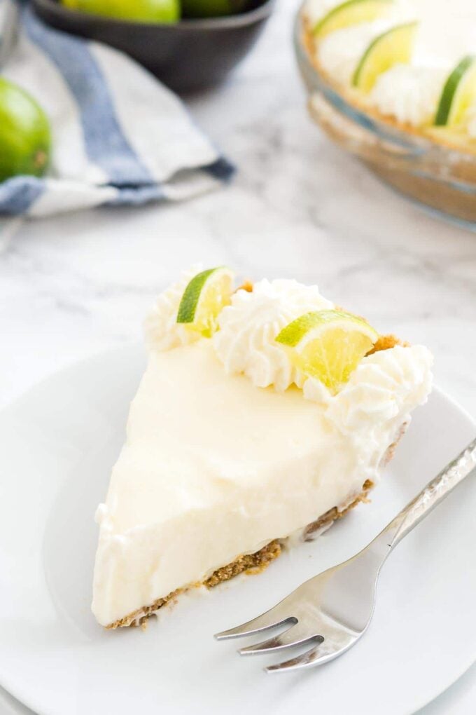 Une part de tarte au citron vert sans cuisson sur une assiette avec une fourchette