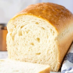 Pain blanc avec la première tranche coupée à côté d'un torchon blanc et bleu