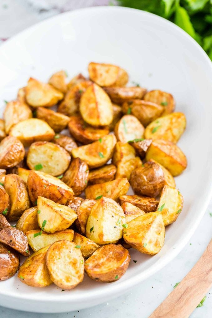 Pommes de terre rôties à la friteuse à air garnies de persil dans un bol blanc