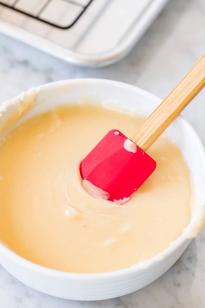 Glacage pour donuts à l'Air Fryer dans un bol blanc avec une spatule rouge