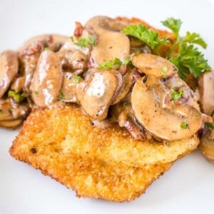 Schnitzel garni de sauce aux champignons et bacon, décoré de persil