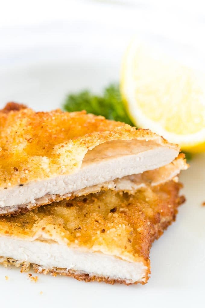 Escalope, coupée en deux, empilée sur une assiette, garnie de citron et de persil